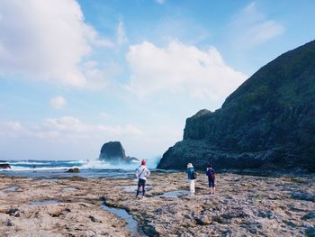 People standing on beach against sky