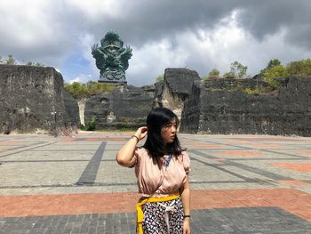 Woman standing by statue against sky