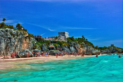 People on beach against blue sky