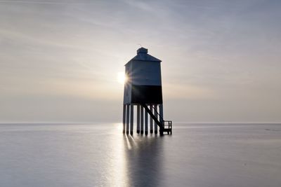 Scenic view of sea against sky with lighthouse during sunset