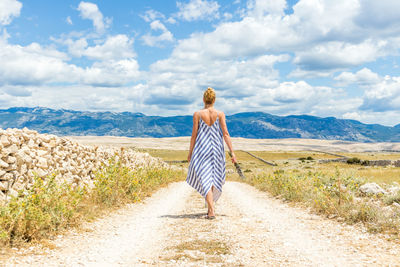 Rear view of woman walking on road against sky