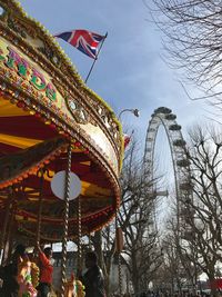 Low angle view of ferris wheel by building against sky