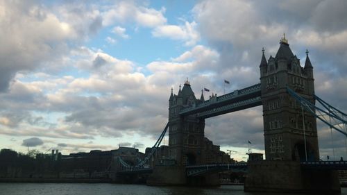 Low angle view of bridge over river against cloudy sky