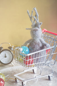 Close-up of baubles and toy in shopping cart on table
