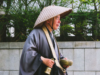 Woman wearing hat standing against plants