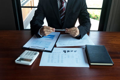 Rear view of man using mobile phone on table