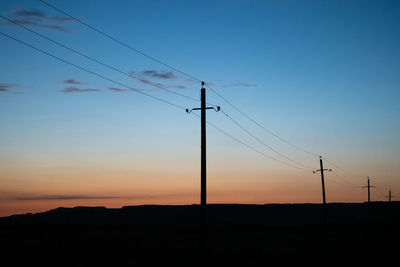 Silhouette electricity pylon against sky during sunset