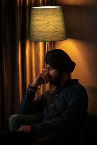 Thoughtful man sitting on sofa in darkroom at home