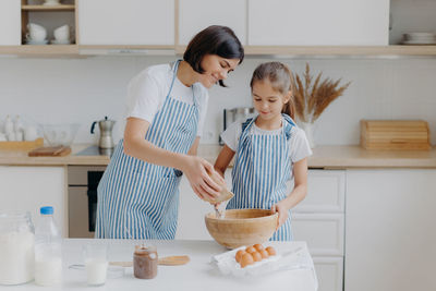 Mother with daughter preparing food in kitchen