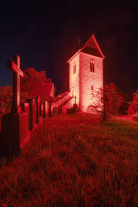 Red building on field against sky at night