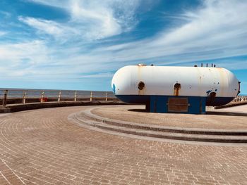 Railing on footpath by sea against sky