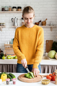 Young woman chopping celery on kitchen counter