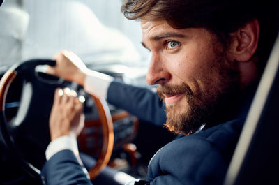 Smiling man wearing suit sitting in car