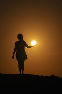 Optical illusion of silhouette woman holding son while standing on land