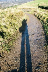 Shadow of man walking on road