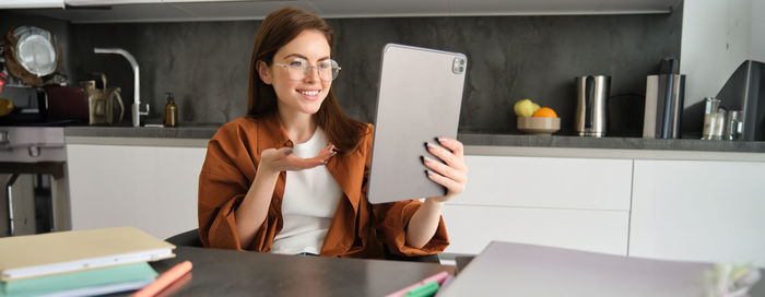 Portrait of young woman using mobile phone at table