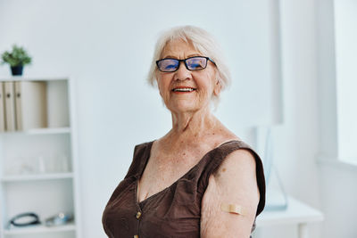 Portrait of smiling woman standing against wall