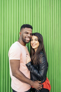 Happy young couple standing against wall