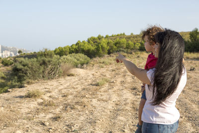 Mother and son in the field indicating where the city is in the distance