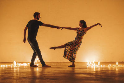 People dancing against orange sky during sunset