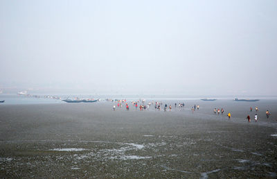 People at beach against sky during rainfall