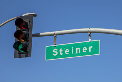 Low angle view of road sign against clear blue sky