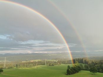 Scenic view of rainbow over landscape against sky