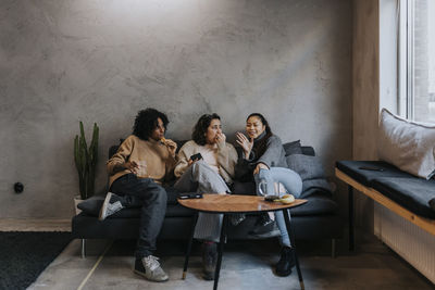 Multiracial female entrepreneurs having snacks and talking with each other in break time at workplace