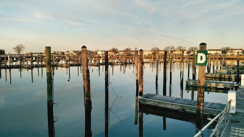 Wooden posts in lake against sky