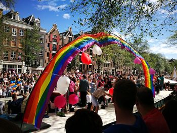 People on multi colored flags against sky in city