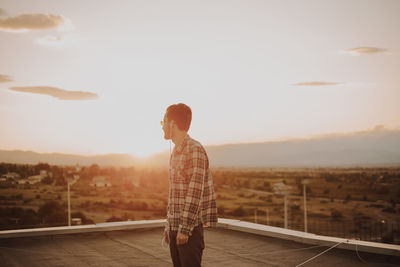 Man standing on terrace against sky during sunset