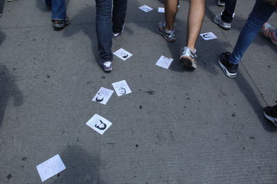 Low section of men walking over posters on footpath