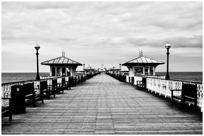 Empty pier over sea against sky