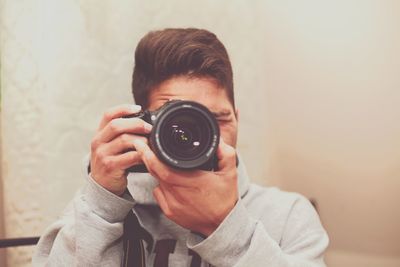 Close-up of man photographing from dslr camera against wall