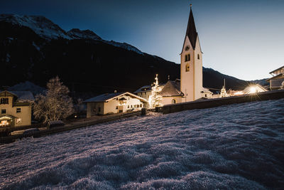 Illuminated building against sky during winter at night