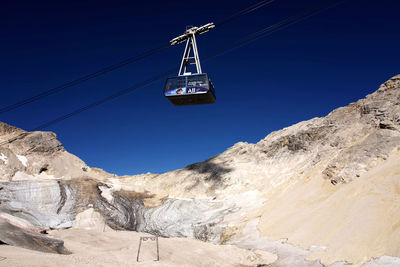 Overhead cable car in mountains against clear blue sky