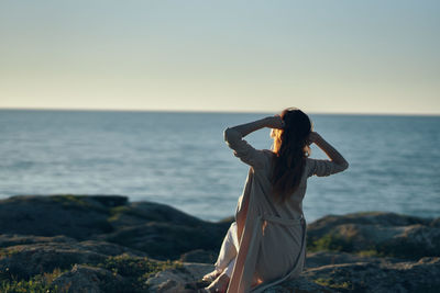 Woman standing in sea against sky