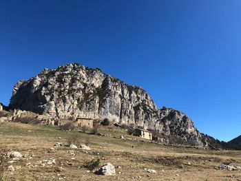 Built structure on rocks against clear blue sky