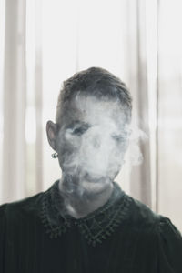 Genderblend man smoking cigarette at home