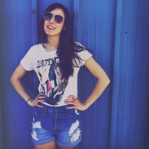 Portrait of woman wearing sunglasses standing against wall