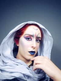 Close-up portrait of young woman with make-up over black background