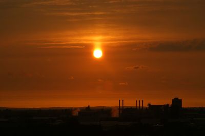 Silhouette cityscape against sky during sunset