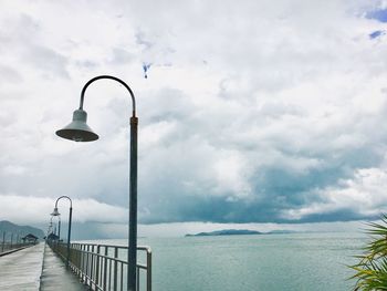 Street light by sea against sky