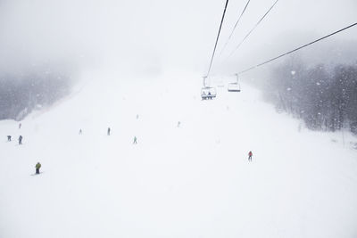 Low angle view of ski lift over snow covered field