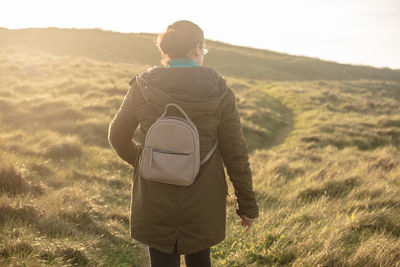 Woman with a small backpack walking through a natural grassland