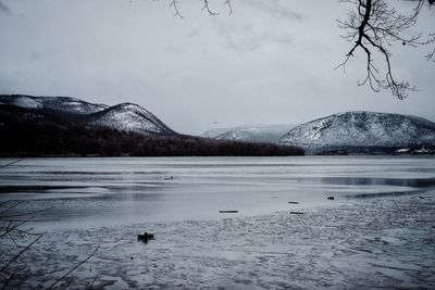 Scenic view of lake by snowcapped mountains against sky