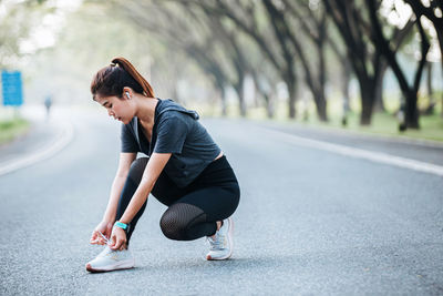 Side view of young woman exercising on road