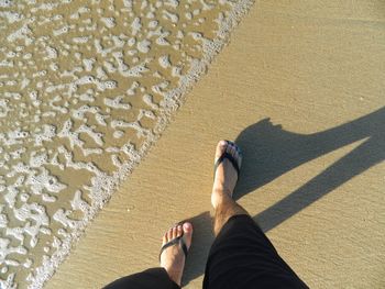 Low section of man walking on shore