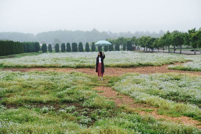 Full length of woman holding umbrella while standing on field