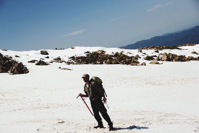 Man standing on snowcapped mountain against sky